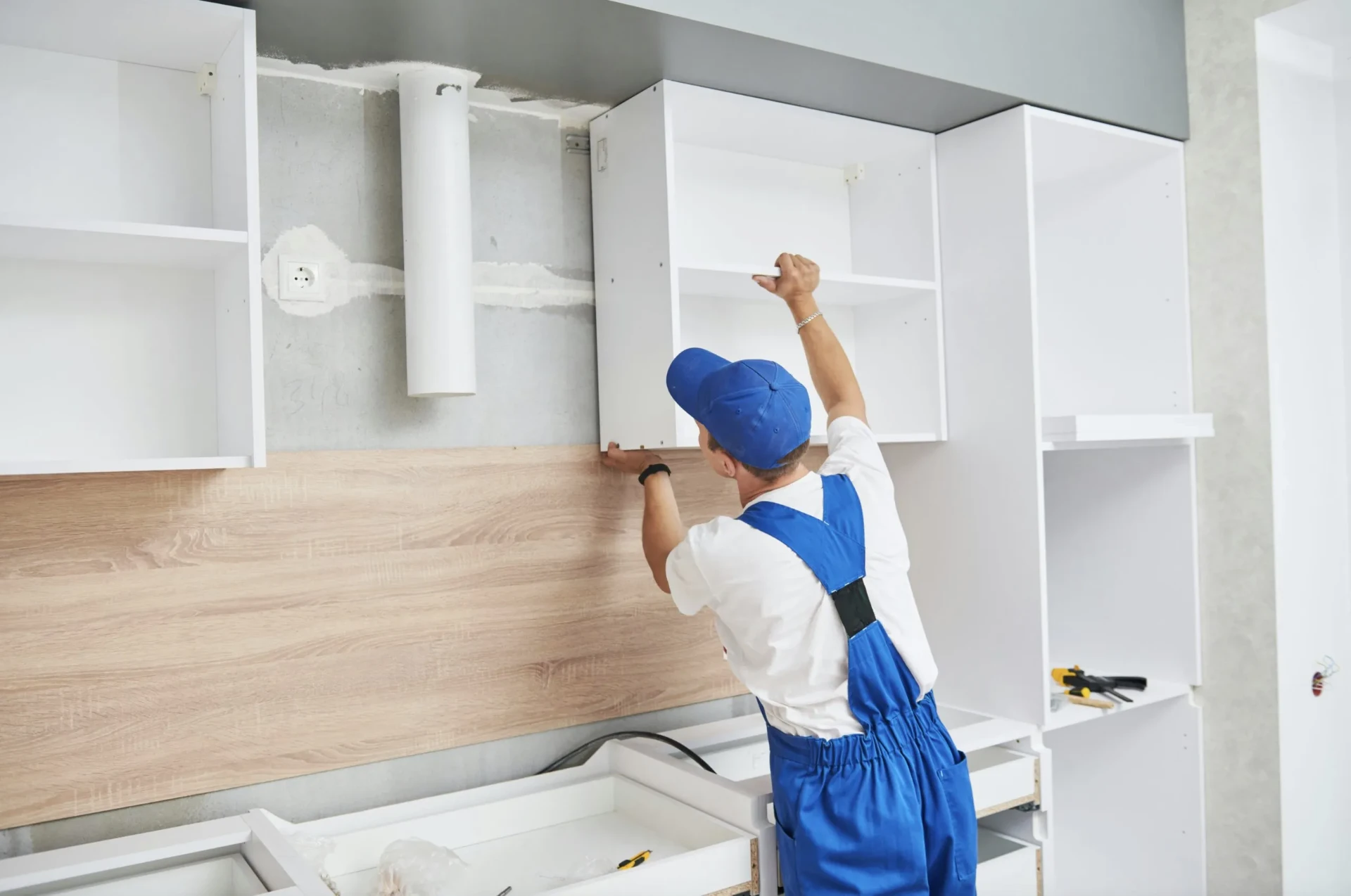 Installer mounting a white wall cabinet during a Golden Beach kitchen project
